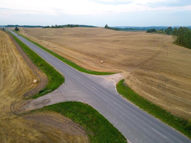 Foto foto de un dron de un campo de trigo verde joven dividido por una carretera vista aérea de un campo agrícola patrones abstractos y líneas rectas en tierras agrícolas