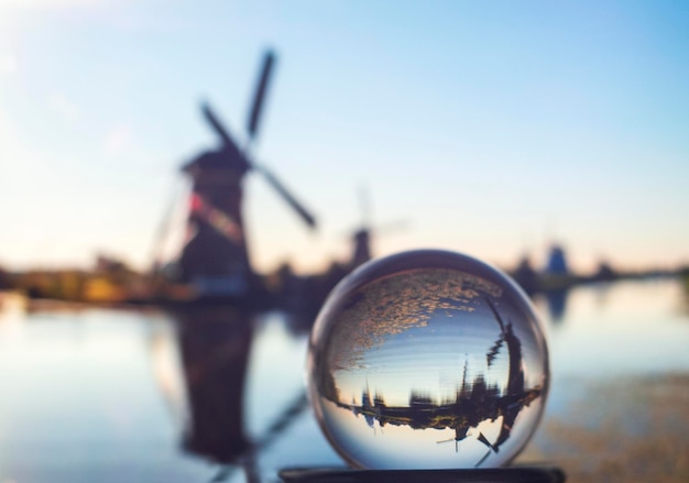 Foto durch eine Glaskugel Spiegelbild des Sonnenuntergangs und der Windmühlen des Kanals in den Niederlanden