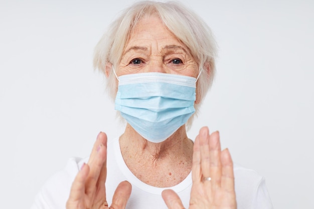 Foto einer alten Dame im Ruhestand in lässigem T-Shirt und medizinischer Maske, isolierter Hintergrund