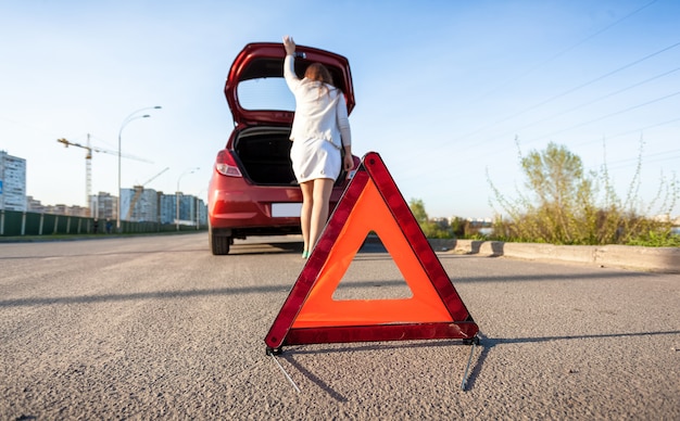 Foto einer Frau, die im Kofferraum eines kaputten Autos schaut