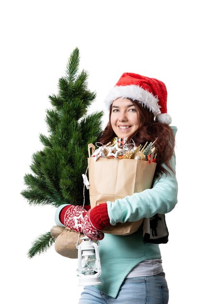 Foto foto einer frau mit weihnachtshut mit weihnachtsbaum-papiertüte in der hand