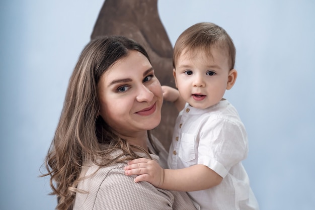 Foto einer glücklichen lächelnden Mutter mit einem kleinen Sohn in ihren Armen.