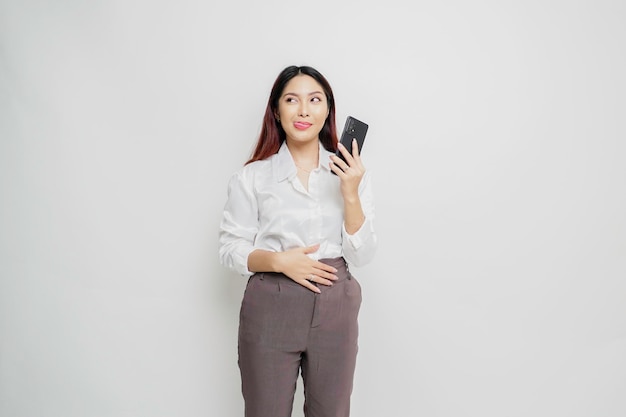 Foto einer hungrigen aufgeregten jungen Frau, die ihr Telefon hält und sich fragt, was sie leckeres Essen einzeln auf weißem Farbhintergrund bestellen soll