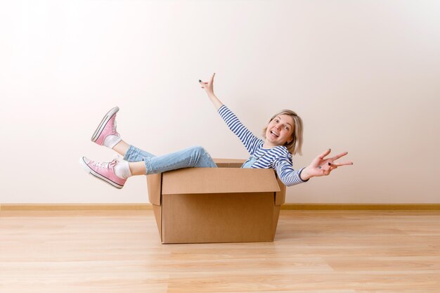 Foto einer jungen Frau, die im Karton sitzt