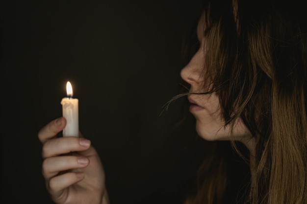 Foto einer Kerze in der Nacht, die von einem jungen Mädchen gehalten wird Konzentrieren Sie sich auf die Kerze Dunkler Hintergrund Gruseliges Horrorkonzept