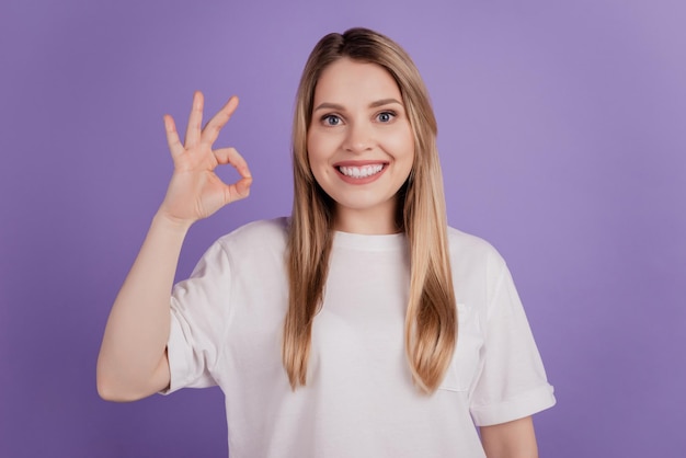 Foto einer netten positiven Dame, die ein Okey-Zeichen zeigt, das die Wahl genehmigt, legere Kleidung auf violettem Hintergrund zu tragen