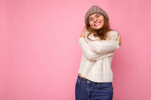 Foto einer schönen, glücklich lächelnden jungen brünetten Frau, die über rosafarbener Hintergrundwand isoliert ist