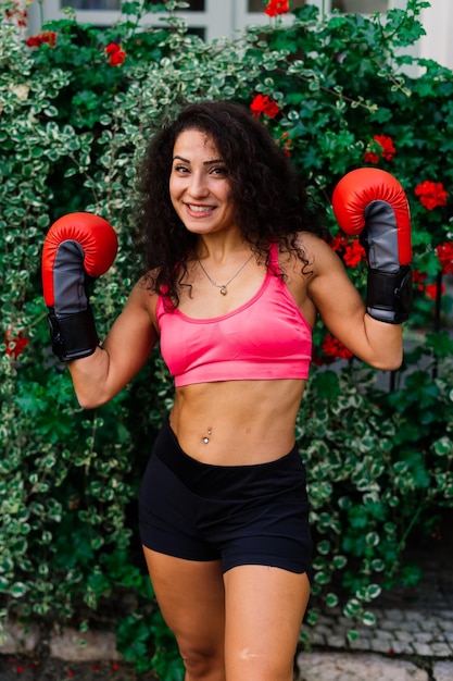 Foto einer starken Fitness-Boxerin in Handschuhen, die im Freien posiert