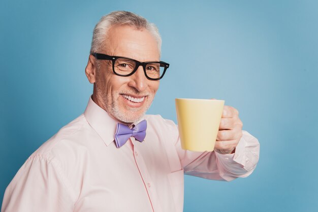 Foto eines alten gutaussehenden Geschäftsmannes, der heißen Kaffee trinkt