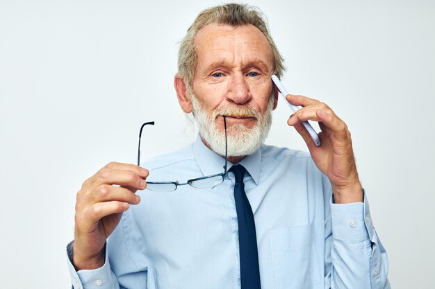 Foto eines alten Mannes im Ruhestand in einem Hemd mit Krawatte mit hellem Hintergrund der Telefontechnologie