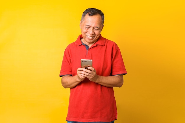 Foto eines asiatischen alten Mannes, der am Telefon lächelt, isoliert auf gelbem Farbhintergrund