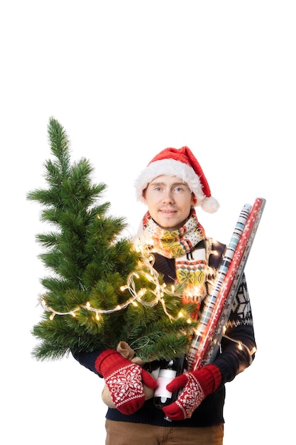 Foto foto eines fröhlichen mannes in weihnachtsmannskappe mit weihnachtsbaum mit girlandenverpackungspapier in den händen