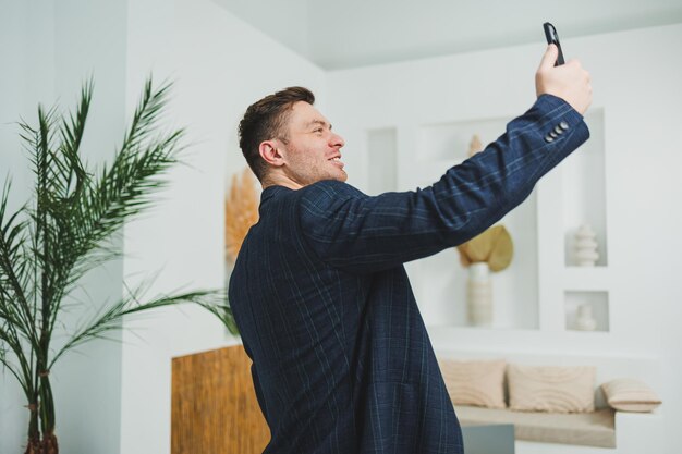 Foto eines glücklichen, hübschen Mannes in einer klassischen Jacke, der am Handy spricht und lächelt.