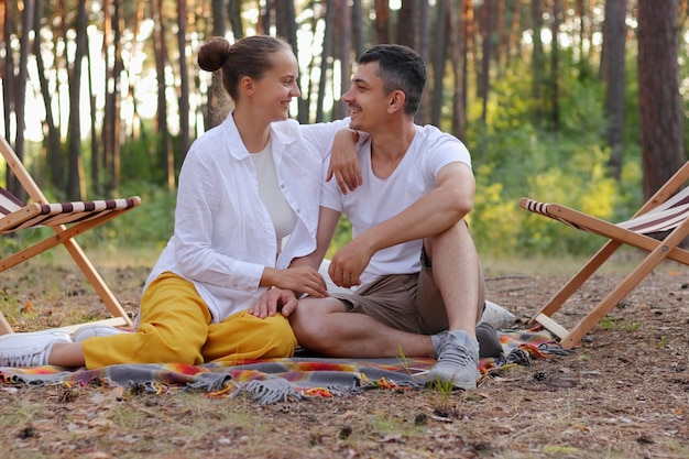 Foto eines gutaussehenden, zufriedenen Paares, das die gemeinsame Zeit genießt, indem es sich liebevoll ansieht und sich umarmt, um romantische Gefühle auszudrücken, schöne Natur