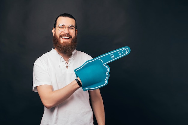 Foto eines jungen bärtigen Hipsters trägt einen blauen Schaumfanhandschuh.