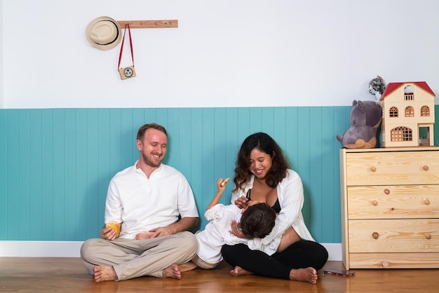 Foto eines jungen, fröhlichen, positiv lächelnden Paares, schwangere Frau und Ehemann mit ihrem Sohn, der sich zu Hause entspannt