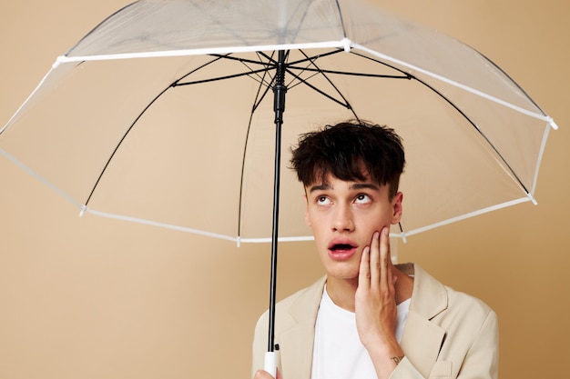 Foto eines jungen Mannes in einer weißen Jacke mit offenem Regenschirm