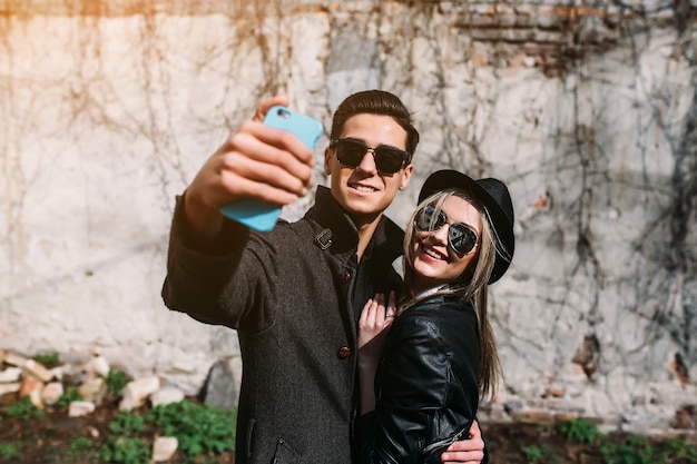 Foto eines jungen schönen Paares, das Selfie auf grauer Wand macht