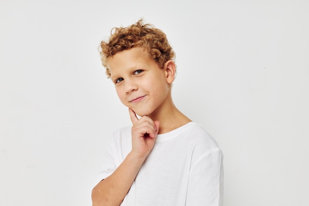 Foto eines kleinen Jungen in einem weißen T-Shirt, das eine unveränderte Spaß-Kindheit aufwirft