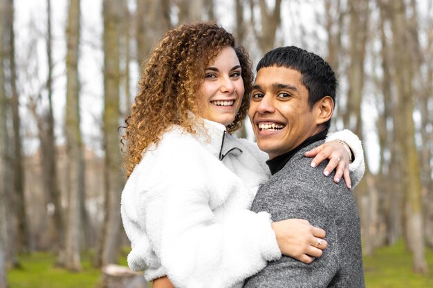 Foto eines lächelnden Paares, das sich in einer Waldumgebung umarmt