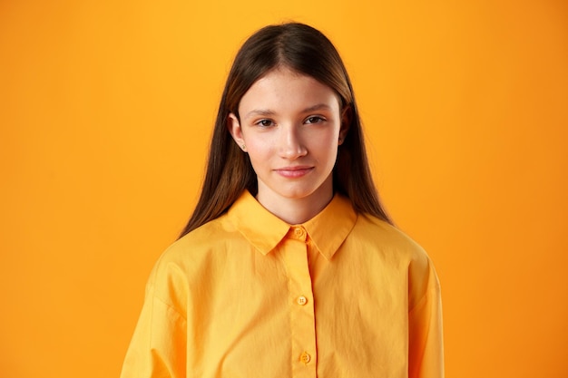 Foto eines lächelnden Teenager-Mädchens vor gelbem Hintergrund im Studio