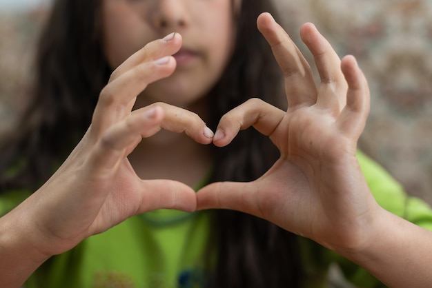 Foto eines lässigen, fröhlichen, süßen, lustigen Mädchens, das mit den Fingern über ihrem Kopf ein Herzformschild zeigt