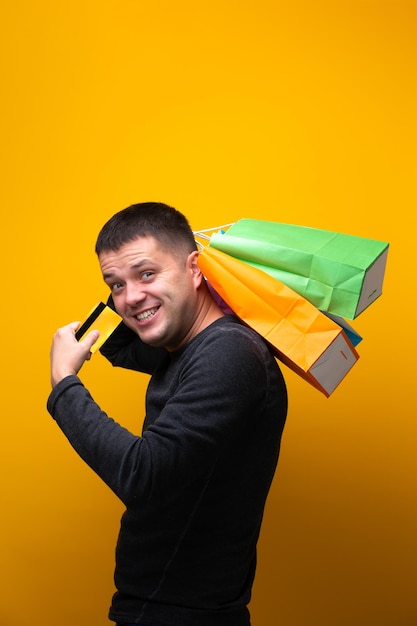 Foto eines Mannes mit Bankkarte und bunten Einkaufstaschen