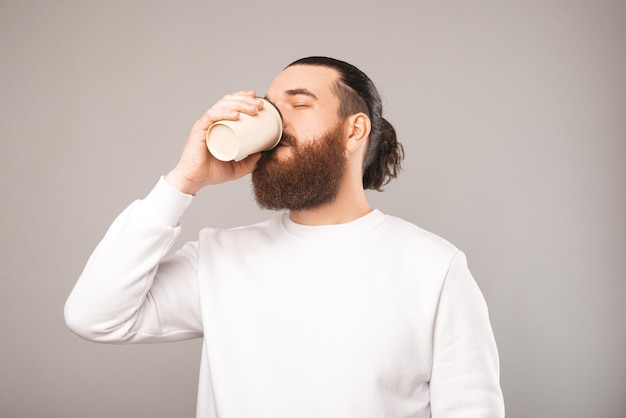 Foto eines müden Büroangestellten, der eine Tasse Kaffee für mehr Kaffee trinkt