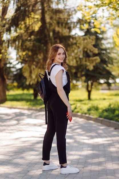 Foto eines positiven fröhlichen Teenager-Mädchens verbringt Zeit im Park und mit Handy.