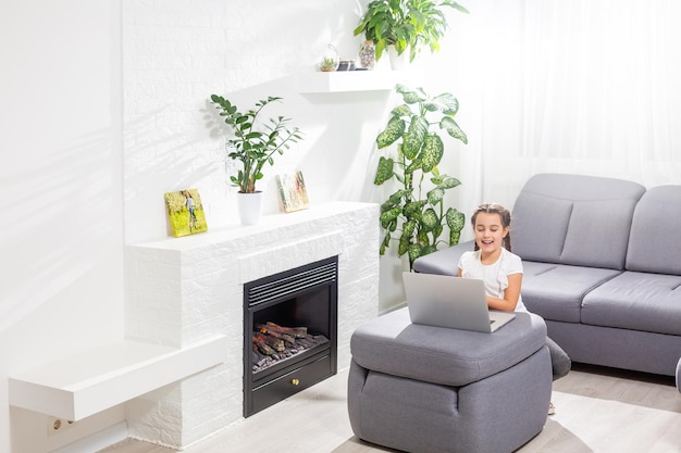 Foto eines positiven Kindermädchens, das einen Remote-Sitz-Schreibtisch-Tisch mit einem Laptop studiert, hat eine Online-Kommunikationsstunde mit einem Tutor, der einen Bericht im Haus schreibt