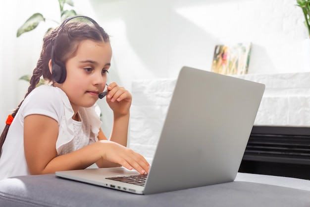 Foto eines positiven Kindermädchens, das einen Remote-Sitz-Schreibtisch-Tisch mit einem Laptop studiert, hat eine Online-Kommunikationsstunde mit einem Tutor, der einen Bericht im Haus schreibt