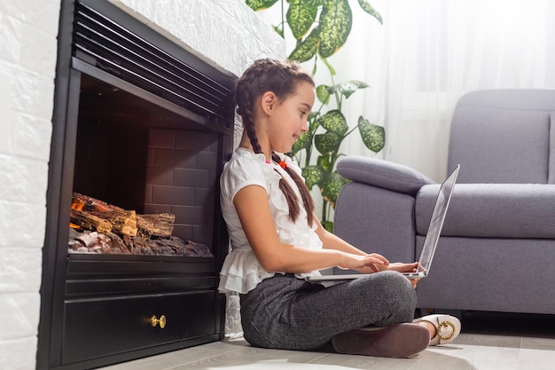 Foto eines positiven Kindermädchens, das einen Remote-Use-Laptop studiert, hat eine Online-Kommunikationsstunde mit einem Tutor, der einen Bericht im Haus schreibt