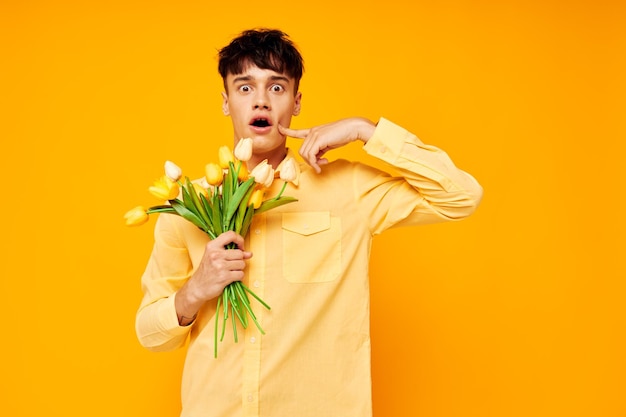 Foto eines romantischen jungen Freundes mit einem Blumenstrauß, der ein Geschenk aufwirft, gelber Hintergrund unverändert