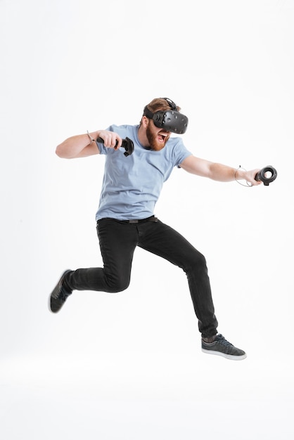 Foto eines verspielten bärtigen Mannes, der ein Virtual-Reality-Gerät trägt und springt.