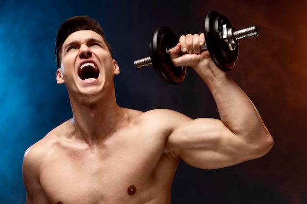 Foto em preto e branco de um belo cara nu esportivo e obstinado construindo músculos