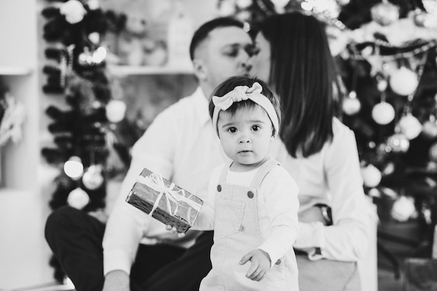 Foto em preto e branco do pai, da mãe com a filha pequena no clima de ano novo