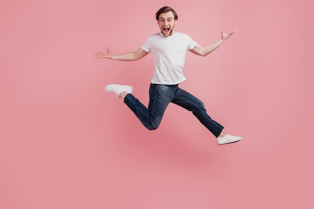 Foto em tamanho grande de um jovem feliz, animado, sorridente, positivo, divirta-se, pule isolado no fundo de cor rosa