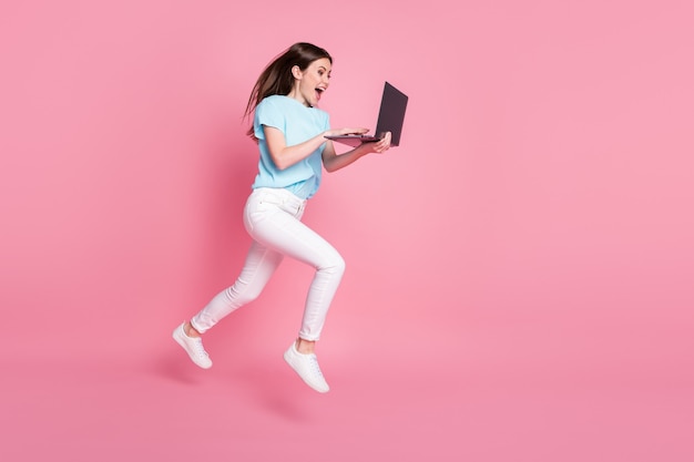 Foto em tamanho real de garota usando laptop com descontos online usar camiseta azul, calça, calça, fundo de cor pastel isolado