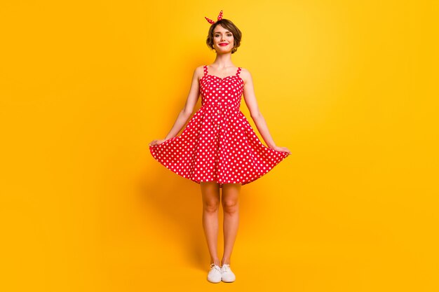 Foto em tamanho real de menina alegre positiva tocando em suas roupas estilo pin-up boa aparência aproveite o tempo livre da primavera isolado sobre uma parede de cores vibrantes