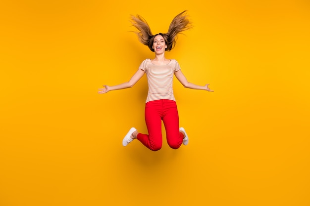 Foto em tamanho real de uma menina divertida alegre e funky tem tempo livre, segurar a mão, sentir uma expressão maluca, pular com seu corte de cabelo caindo voando, vestir uma camiseta estilo casual isolada de cor brilhante