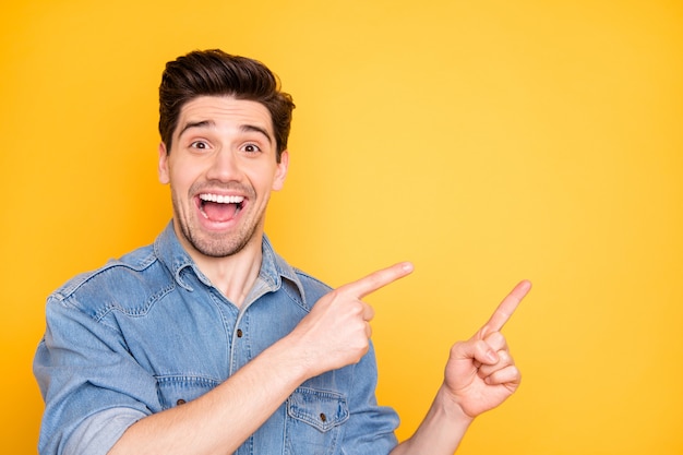 Foto de emocionado extasiado hombre lleno de alegría gritando apuntando al espacio vacío en las ventas con asombro en la cara aislada pared de colores vivos