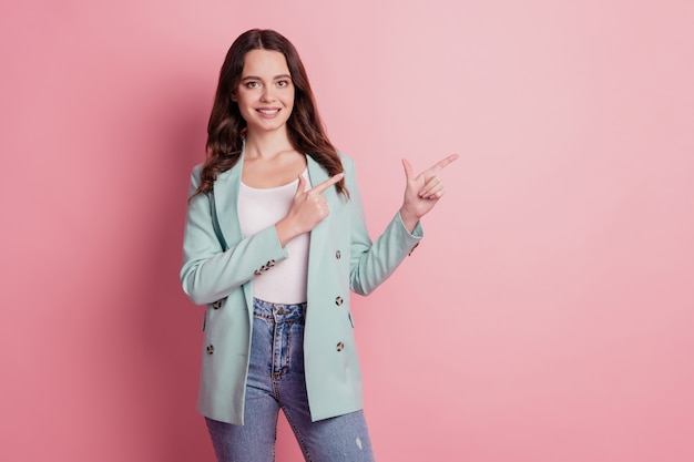 Foto de encantadora dama linda con los dedos directos en el espacio vacío en traje de moda sobre fondo rosa