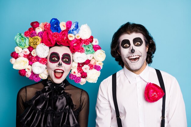 Foto foto de encantadora pareja espeluznante hombre dama sorprendida boca abierta tener descuento un día volver a la vida usar vestido negro traje de muerte rosas diadema tirantes fondo de color azul aislado