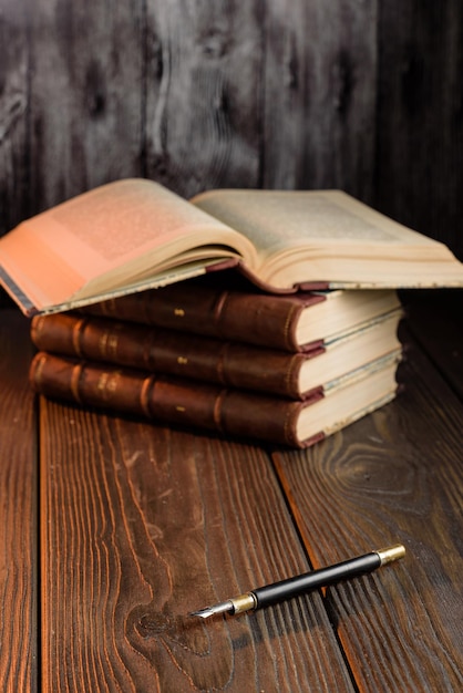 Foto foto de enfoque selectivo de una vieja pluma estilográfica y una pila de libros antiguos