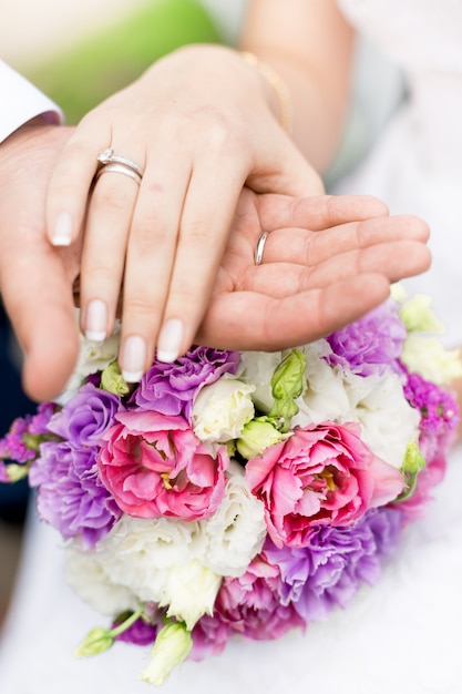 Foto de enfoque suave de primer plano del novio sosteniendo la mano de las novias en el ramo de novia