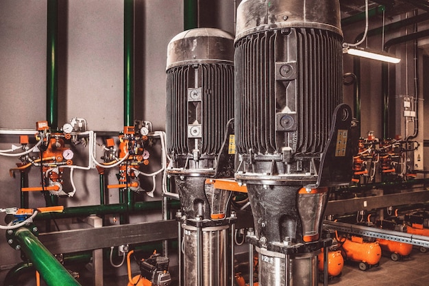 Foto enthält Filmkorn. Wasserpumpstation und Pipeline mit Tanks in einem Industrieraum zur Bereitstellung von Hochdruckwasser für Feuerwehraufgaben. Sprinklerrohre und Steuerungssystem zur Bereitstellung von Trinkwasser