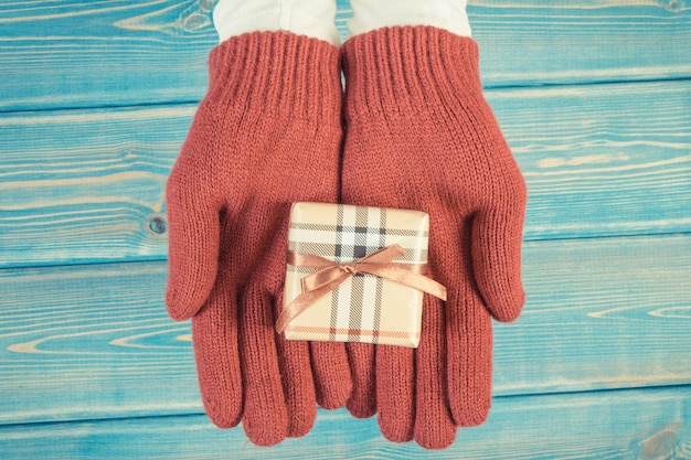 Foto de época Manos de mujer en guantes con regalo para Navidad u otra celebración