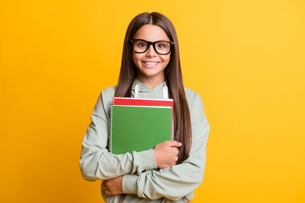 Foto de la escuela, persona, sonrisa, brazos, sujetar libro, llevar, anteojos, aislado, en, brillante, color amarillo, plano de fondo