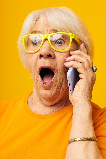 Foto del estilo de vida feliz de la anciana jubilada en camisetas amarillas con fondo aislado del teléfono