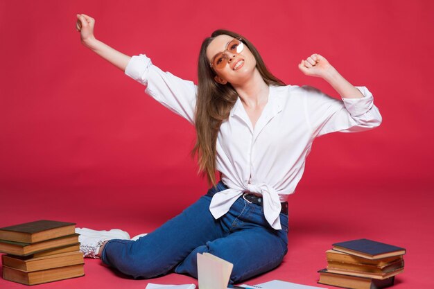 Foto de una estudiante decepcionada usando libros de ejercicios mientras se sienta en el suelo